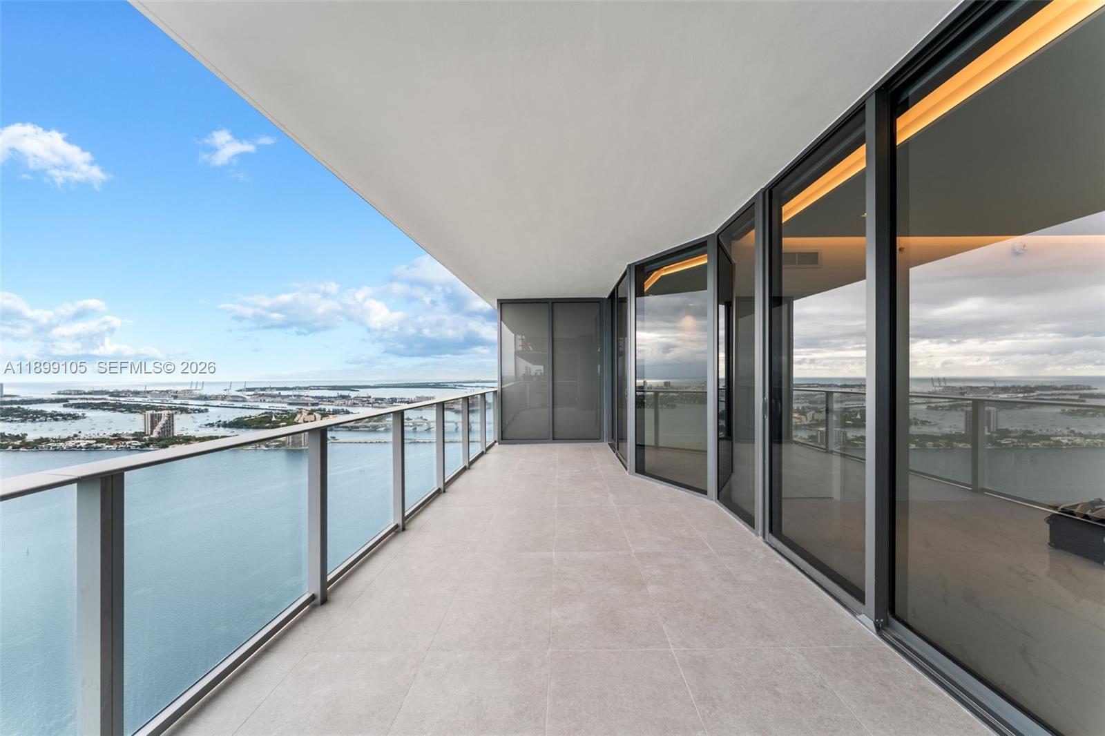 A spacious balcony with glass railings overlooks a bay and city skyline — 700 NE 24th St # 5401, Miami FL 33137, MIAMI, FL