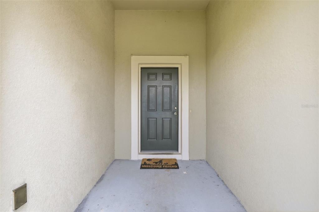 A gray front door with four rectangular windows sits at the end of a porch — 3505 SPRITE LANE, ST CLOUD, FL