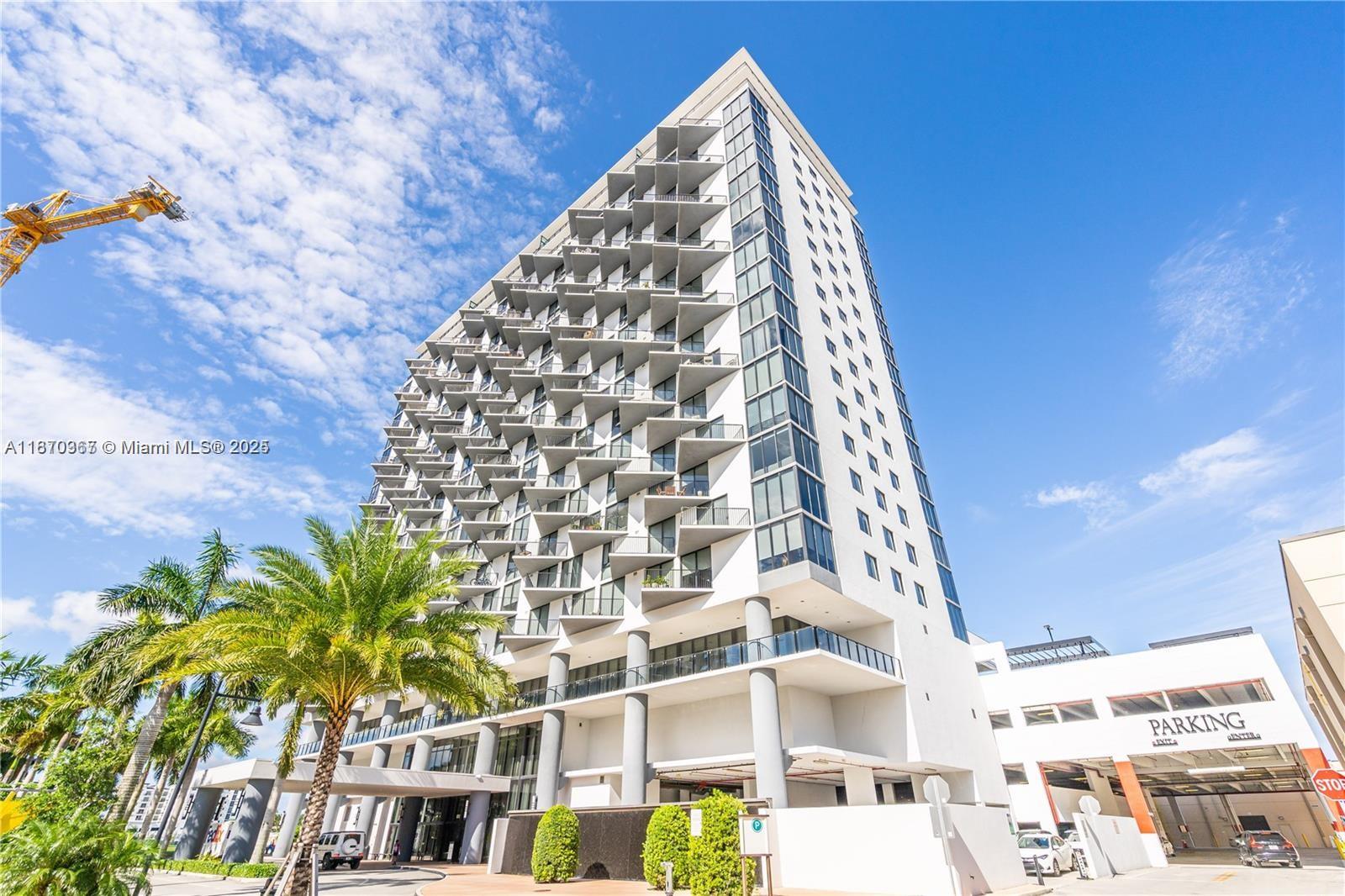 A modern high-rise apartment building features a distinctive zigzag balcony design and an adjacent parking garage — 5252 NW 85th Ave # 1909, Doral FL 33166, DORAL, FL