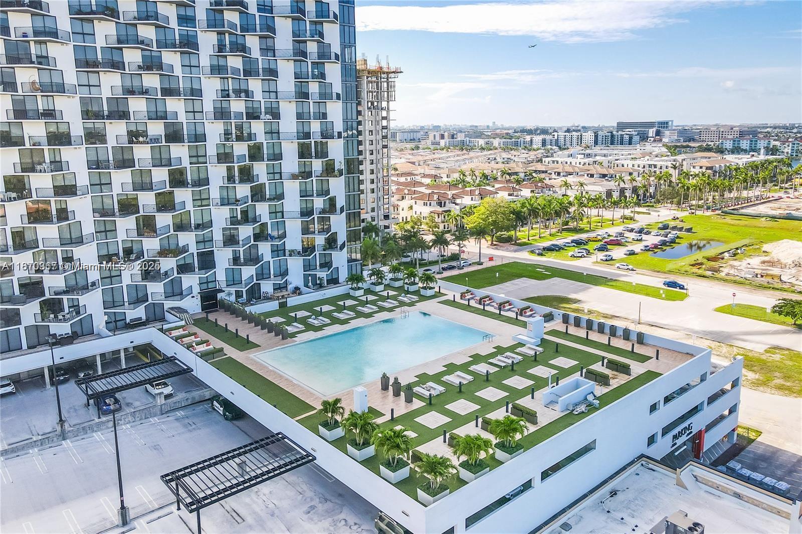 An aerial view shows a high-rise apartment building with an outdoor pool deck and parking — 5252 NW 85th Ave # 1909, Doral FL 33166, DORAL, FL