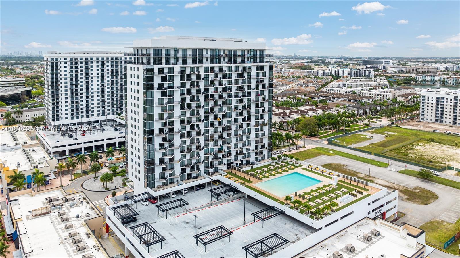 An aerial view shows a tall residential building with an attached parking garage and pool — 5252 NW 85th Ave # 1909, Doral FL 33166, DORAL, FL