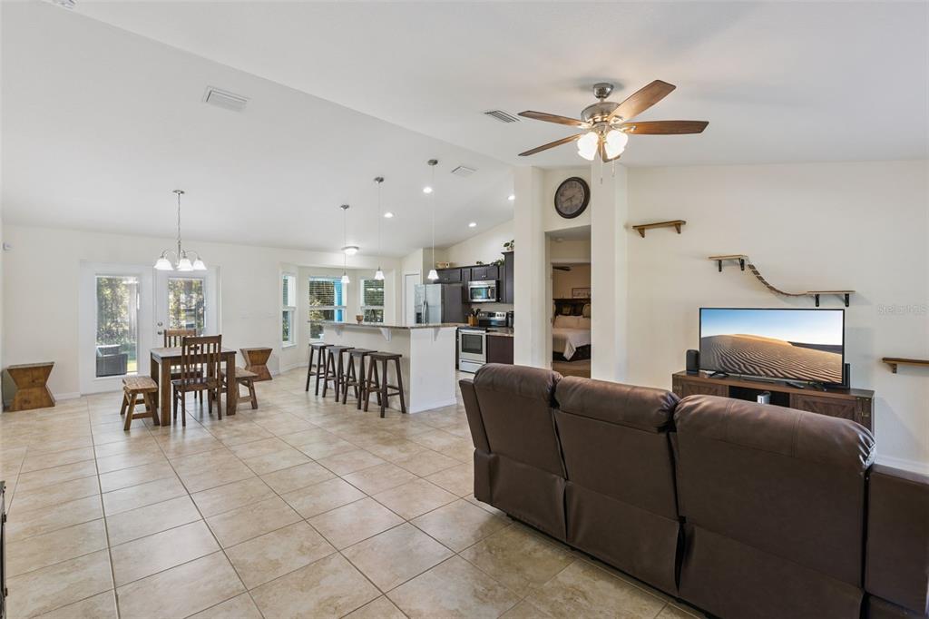 An open-concept living and dining area features tile flooring, a kitchen island, and vaulted ceilings — 7042 SE 122ND LANE, BELLEVIEW, FL