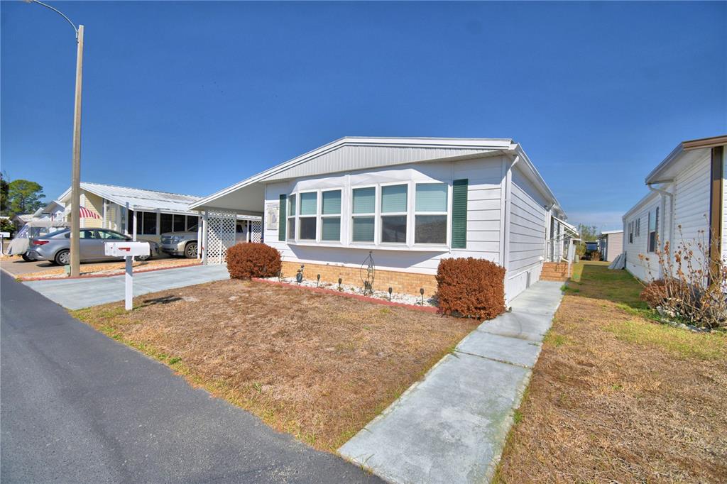 A white manufactured home with a bay window, carport, and a concrete walkway — 4239 CEDARWOOD STREET, WINTER HAVEN, FL