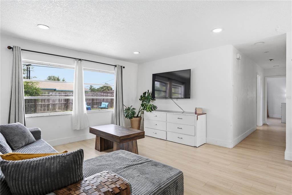 A living room features light wood flooring, a gray sectional sofa, and a wall-mounted television — 835 MARLOWE, ORLANDO, FL