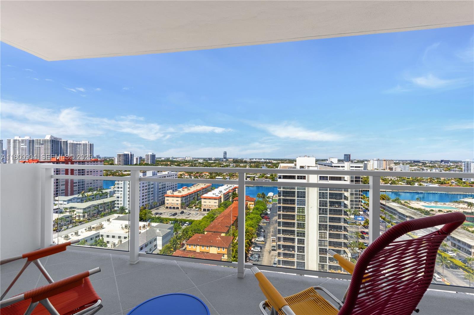A balcony with two colorful chairs overlooks a city skyline and a blue waterway — 2030 S Ocean Dr # 1707, Hallandale Beach FL 33009, HALLANDALE BEACH, FL