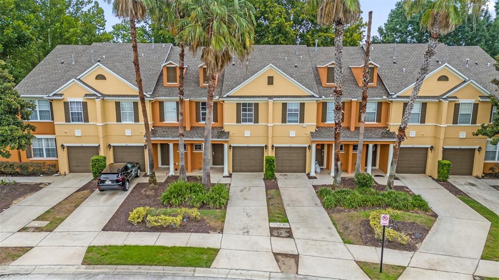 An exterior view of a multi-unit townhouse complex with attached garages and palm trees — 815 ASSEMBLY COURT, KISSIMMEE, FL
