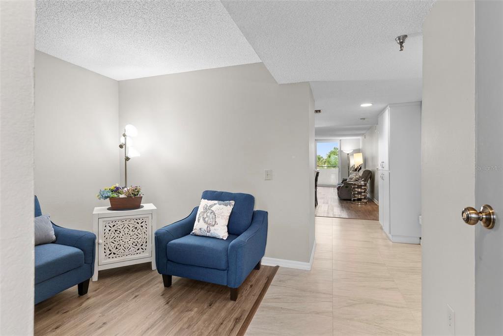 A living room with wood-look flooring, a gray sofa, a television, and an open kitchen — 6035 SEA RANCH DRIVE UNIT 209, HUDSON, FL