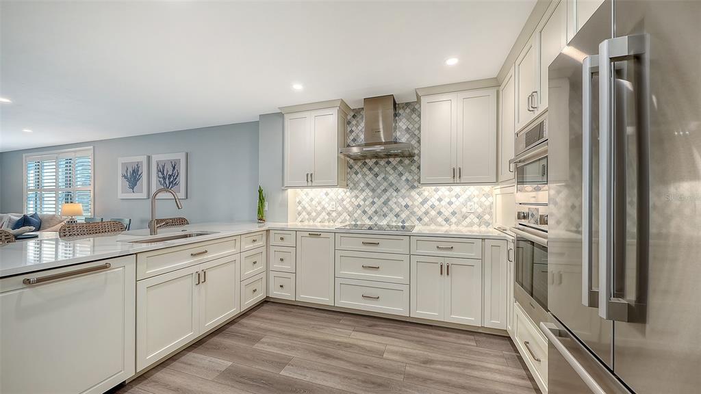 A modern kitchen features white cabinetry, stainless steel appliances, and a patterned tile backsplash — 5780 MIDNIGHT PASS ROAD UNIT 110, SARASOTA, FL