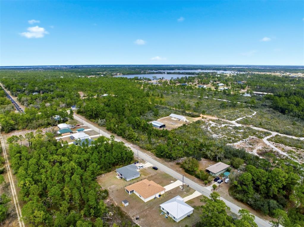 An aerial view shows several houses situated along a road surrounded by dense forest — 6705 BALSAM PLACE, SEBRING, FL