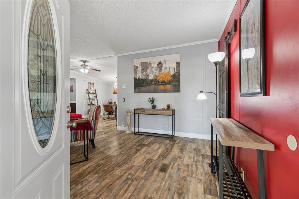 An entryway with wood-look flooring leads into a living area featuring a red accent wall — 17114 BRITTLE ROAD, BROOKSVILLE, FL