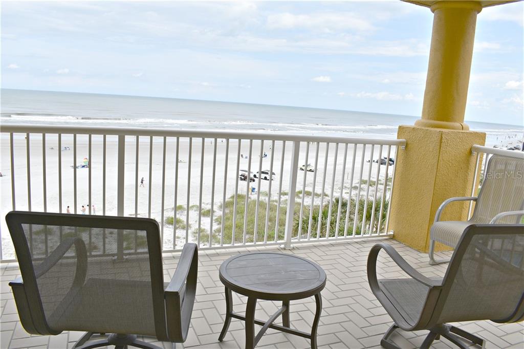 A balcony with patio furniture overlooks a sandy beach and the ocean — 701 N ATLANTIC AVENUE W UNIT 401, NEW SMYRNA BEACH, FL