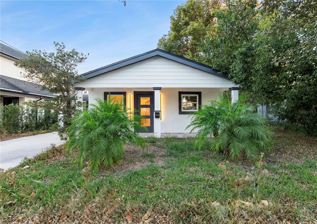 A small, white, single-story house with a dark door and two palm trees in front — 1354 INDIANA AVENUE, WINTER PARK, FL