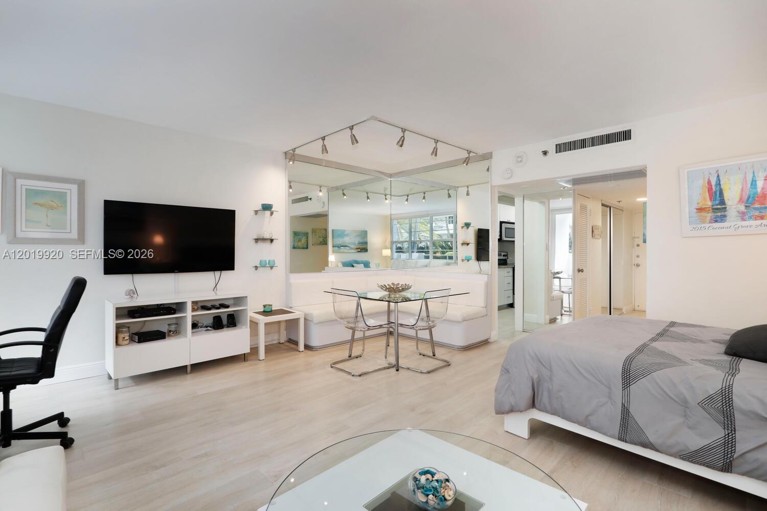 A studio apartment features a dining nook with mirrored walls, a television, and a bed — 100 Lincoln Rd # 330, Miami Beach FL 33139, MIAMI BEACH, FL