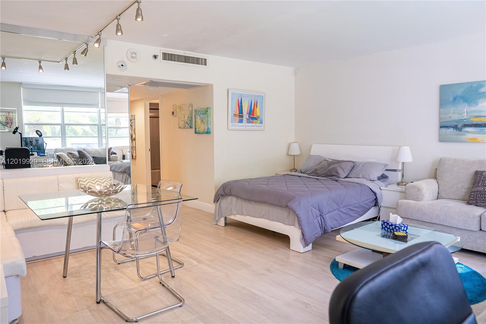 A studio apartment features a bed, dining area with glass table, and light wood flooring — 100 Lincoln Rd # 330, Miami Beach FL 33139, MIAMI BEACH, FL