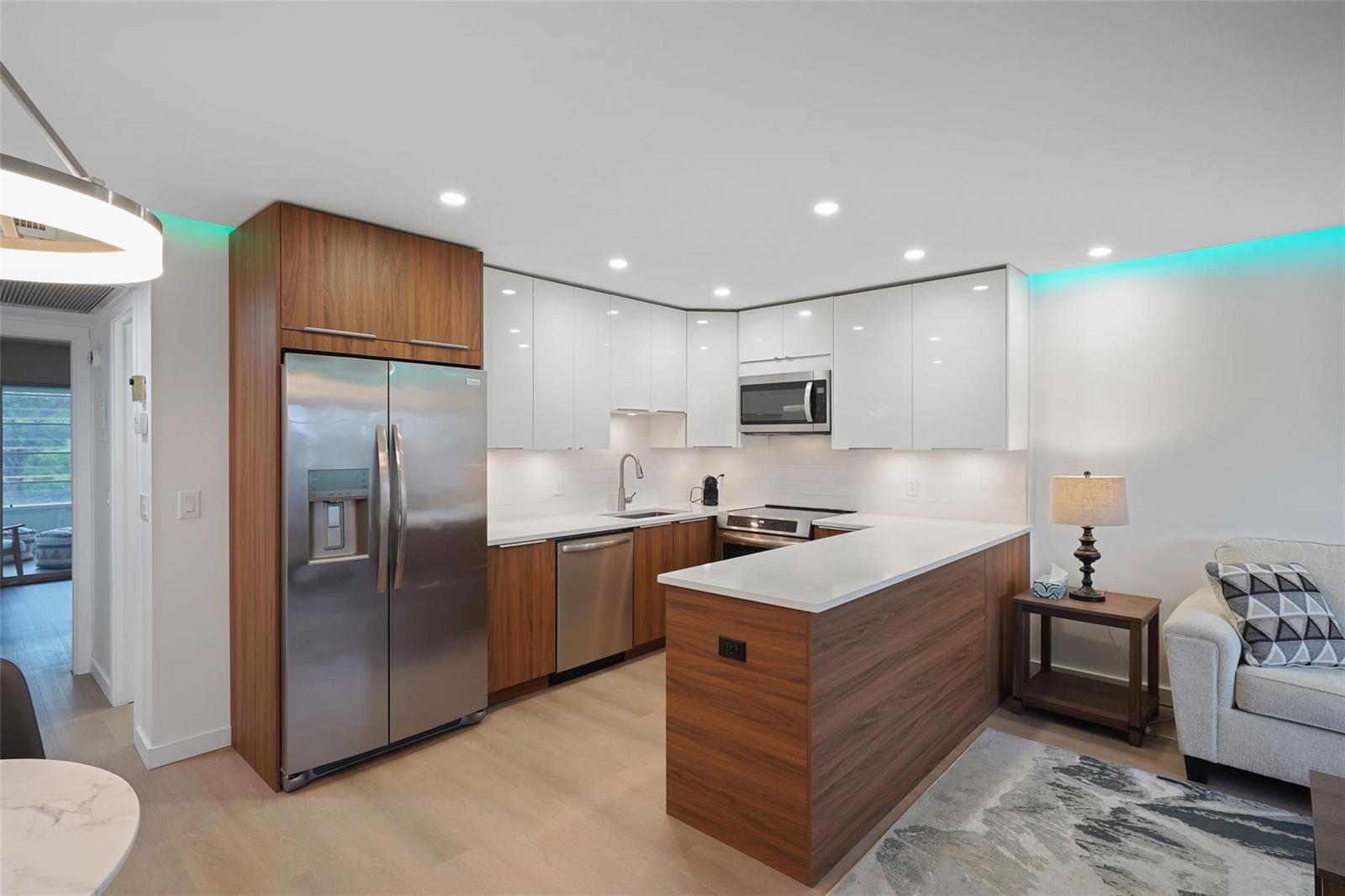 A modern kitchen features wood-tone lower cabinets, white upper cabinets, and a peninsula countertop — 3034 Berkshire B # 3034, Deerfield Beach FL 33442, DEERFIELD BEACH, FL