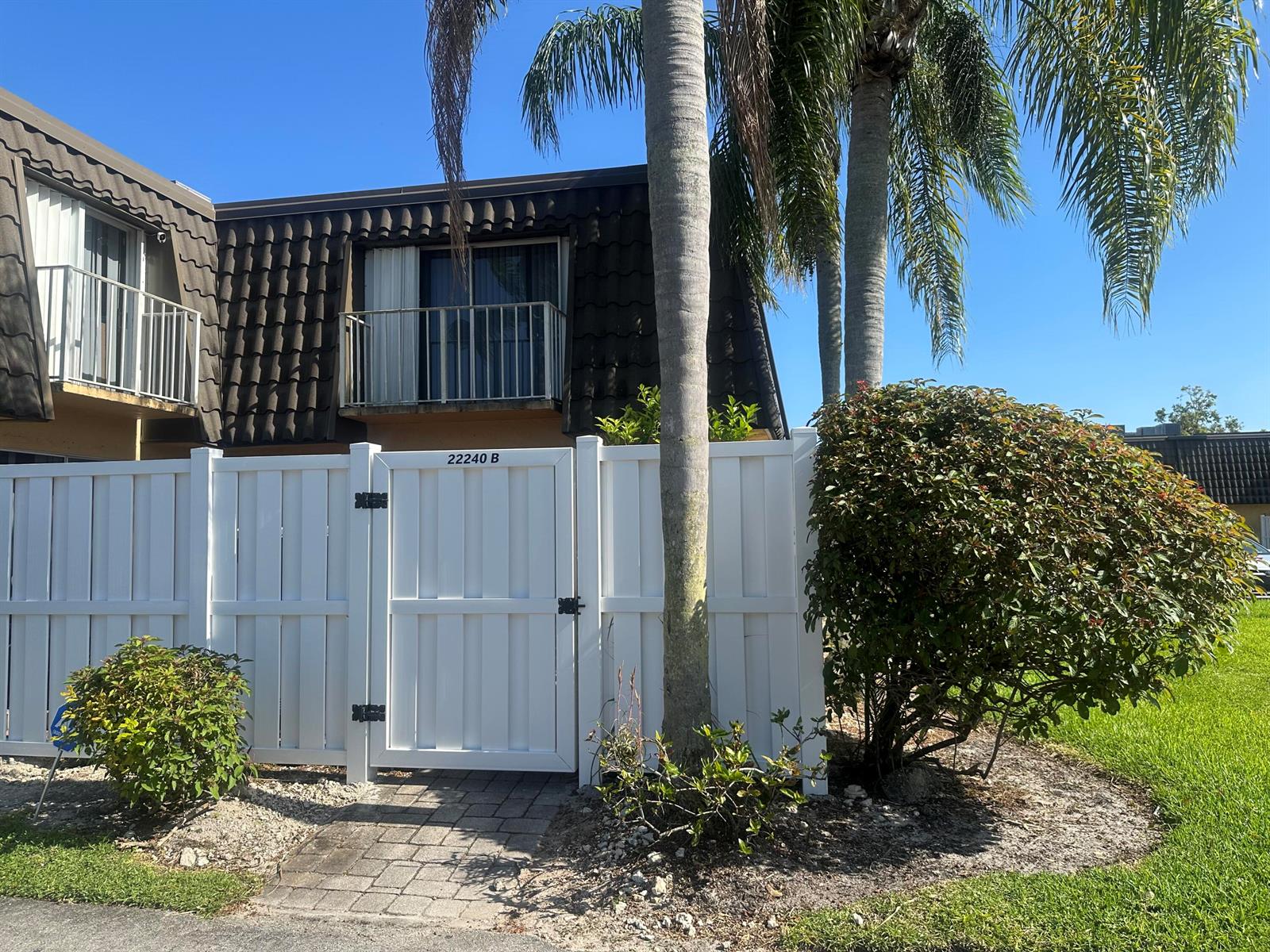 A white vinyl fence with a gate stands in front of a two-story building — 22240 Boca Rancho Drive # B, Boca Raton FL 33428, BOCA RATON, FL