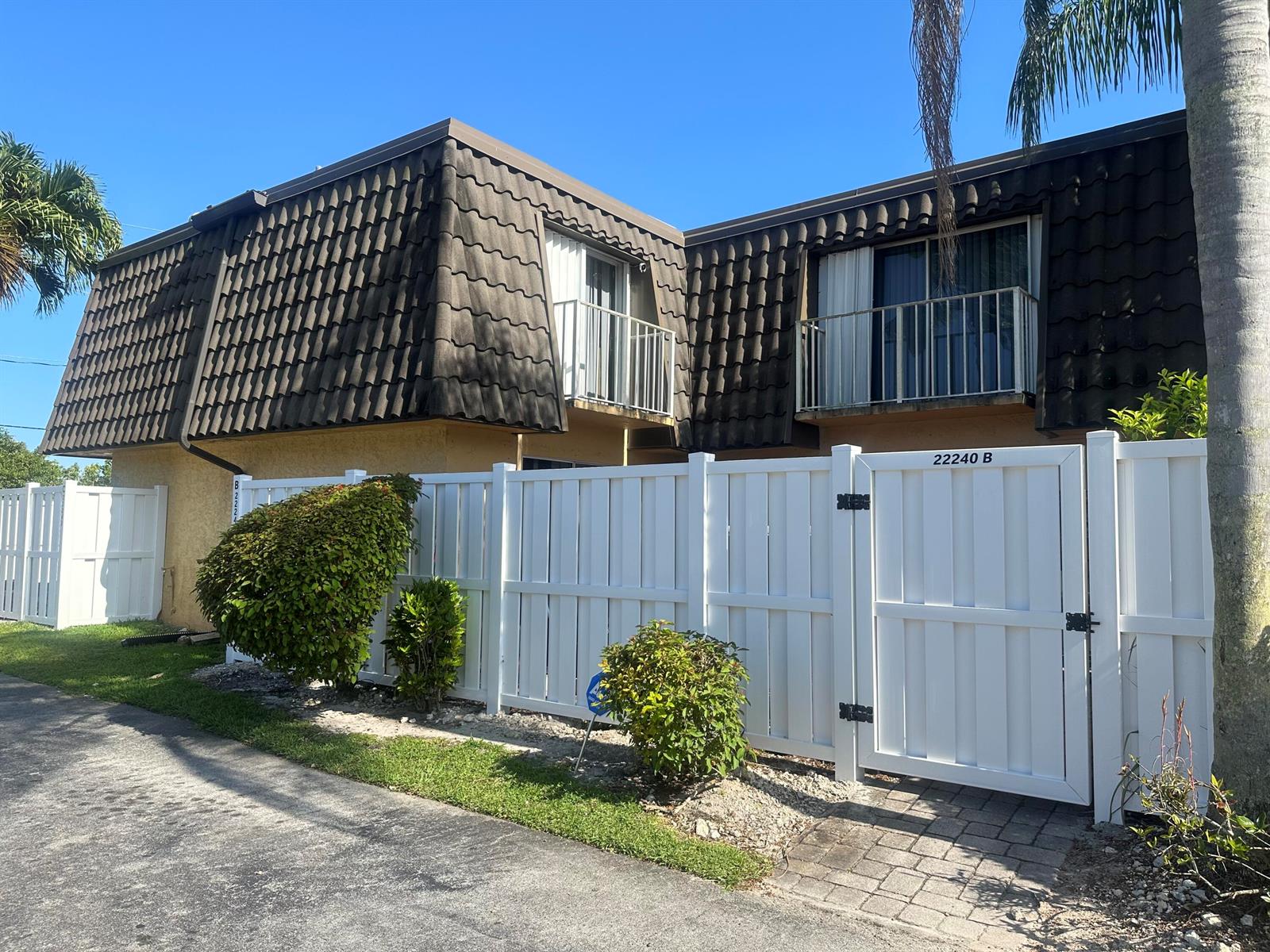 A two-story building with a dark tiled mansard roof and white balconies behind a fence — 22240 Boca Rancho Drive # B, Boca Raton FL 33428, BOCA RATON, FL