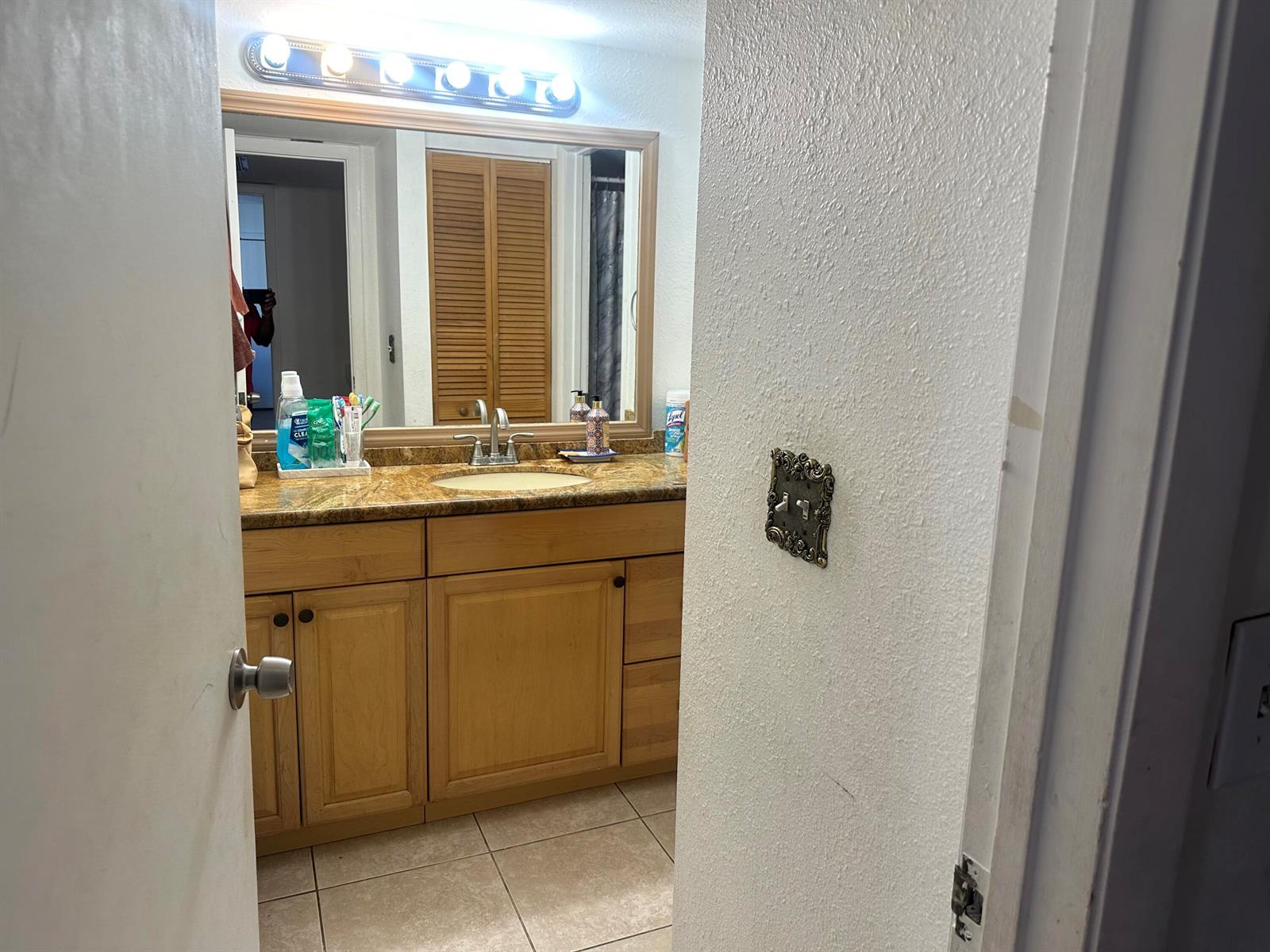 A bathroom features a wood vanity, granite countertop, large mirror, and a decorative light switch — 22240 Boca Rancho Drive # B, Boca Raton FL 33428, BOCA RATON, FL