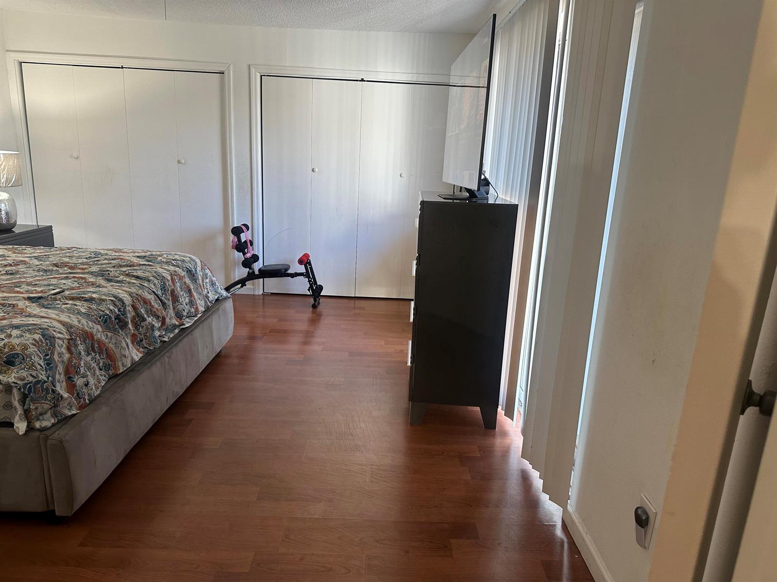 A bedroom with wood-look flooring, a bed, a dresser with a television, and closet doors — 22240 Boca Rancho Drive # B, Boca Raton FL 33428, BOCA RATON, FL
