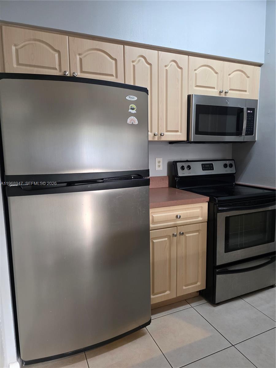 A kitchen features light wood cabinets, stainless steel appliances, and a pink laminate countertop — 18316 NW 68th Ave # C, Hialeah FL 33015, HIALEAH, FL