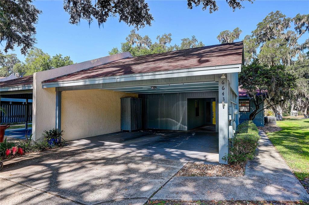 A covered carport with a concrete driveway sits in front of a single-story residential building — 6643 TRAIL RIDGE DRIVE UNIT 00, LAKELAND, FL