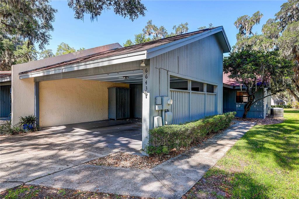 A blue-sided house features a covered carport and a concrete walkway leading to the entrance — 6643 TRAIL RIDGE DRIVE UNIT 00, LAKELAND, FL