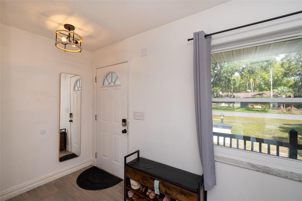 An entryway features a white front door, a shoe bench, a wall mirror, and a window — 2131 HAINLIN COURT, DELTONA, FL