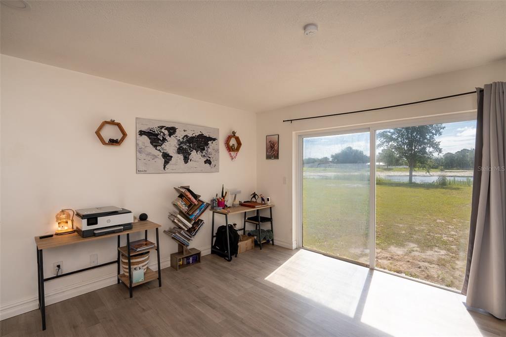 A room with light wood-look flooring, two desks, a bookshelf, and a sliding glass door — 2131 HAINLIN COURT, DELTONA, FL