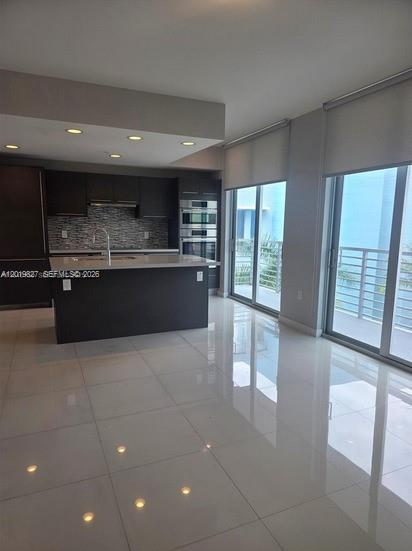 A modern kitchen with dark cabinetry and a central island overlooks a balcony through glass doors — 7875 NW 107th Ave # 412, Doral FL 33178, DORAL, FL