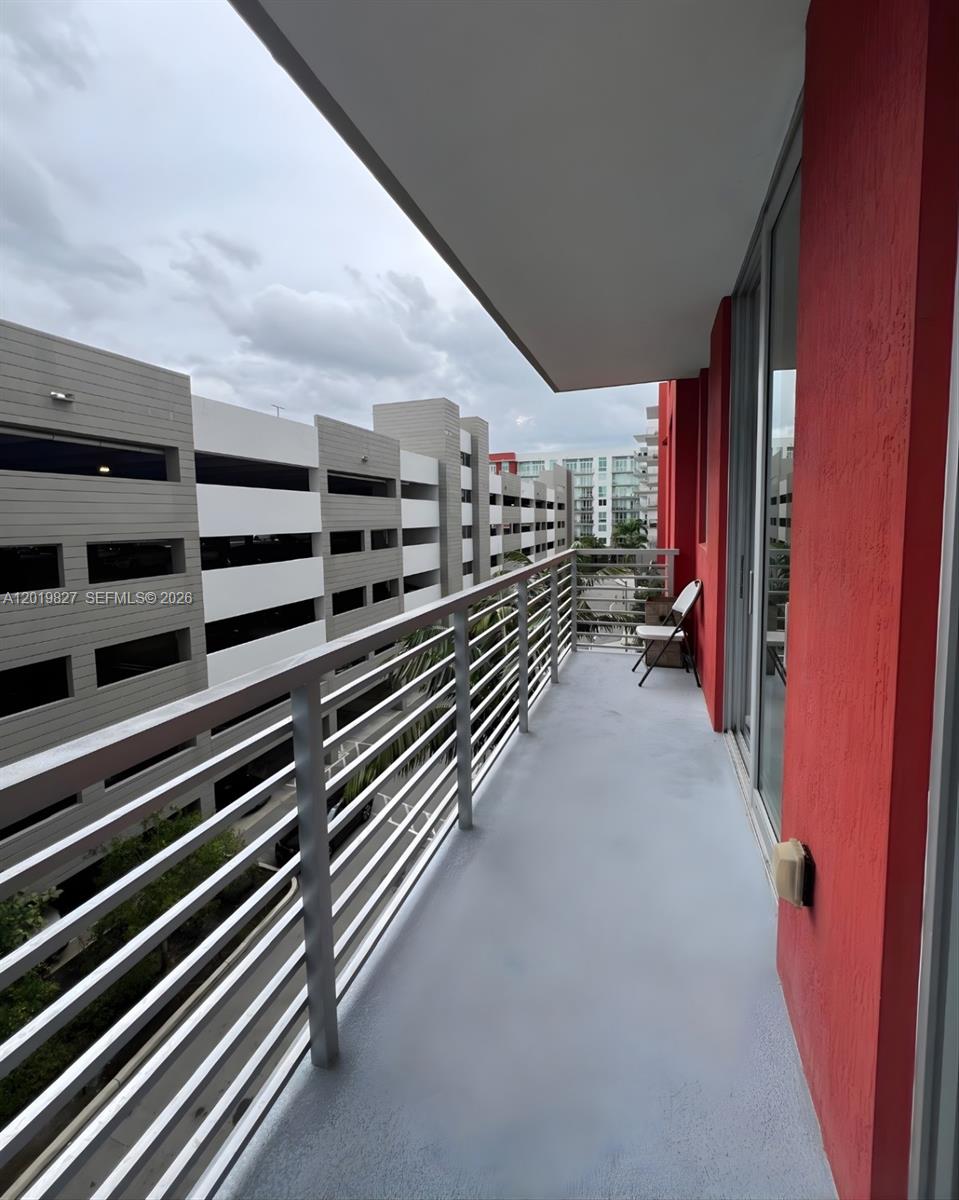 A balcony with a metal railing overlooks a parking garage under a cloudy sky — 7875 NW 107th Ave # 412, Doral FL 33178, DORAL, FL