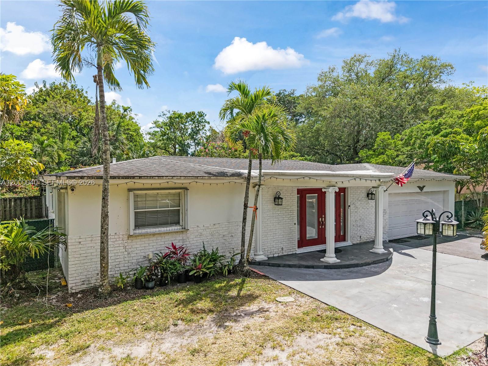 A single-story house with a white brick facade, red double doors, and two palm trees — 4020 SW 2nd St, Plantation FL 33317, PLANTATION, FL
