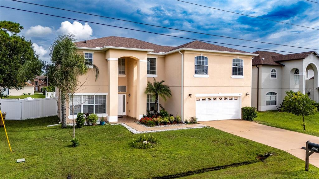 A two-story tan stucco house with a white garage and a front lawn — 525 VICEROY COURT, KISSIMMEE, FL