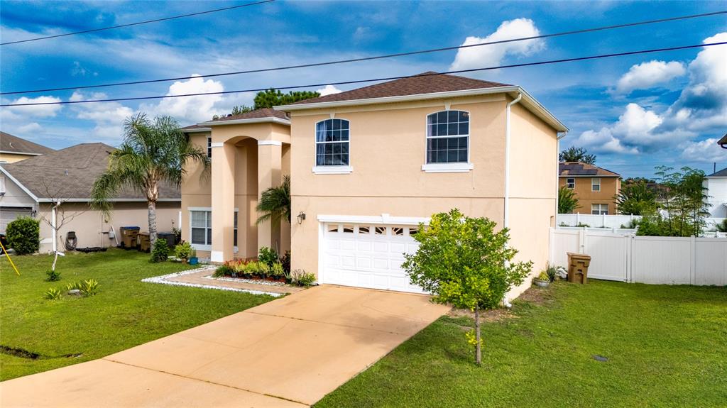 A two-story beige house with a white garage door and a concrete driveway — 525 VICEROY COURT, KISSIMMEE, FL
