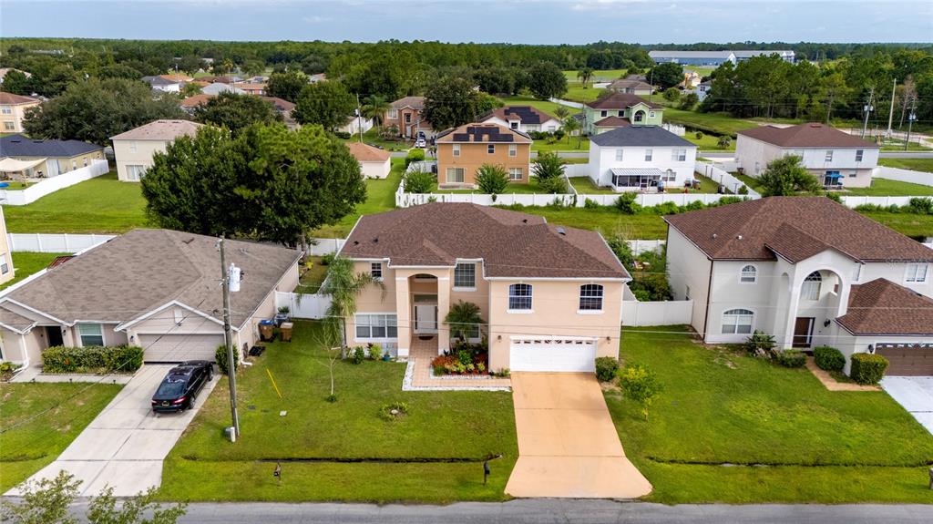 An aerial view shows three suburban houses with brown roofs and driveways in a residential neighborhood — 525 VICEROY COURT, KISSIMMEE, FL