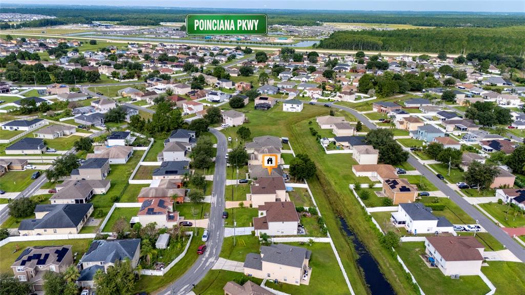An aerial view shows a suburban neighborhood with houses, streets, and a green parkway sign — 525 VICEROY COURT, KISSIMMEE, FL