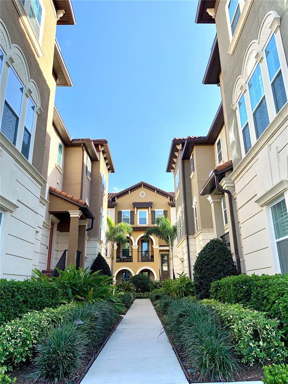 A narrow concrete walkway leads between two multi-story apartment buildings toward a central courtyard — 1220 LOBELIA DRIVE, LAKE MARY, FL