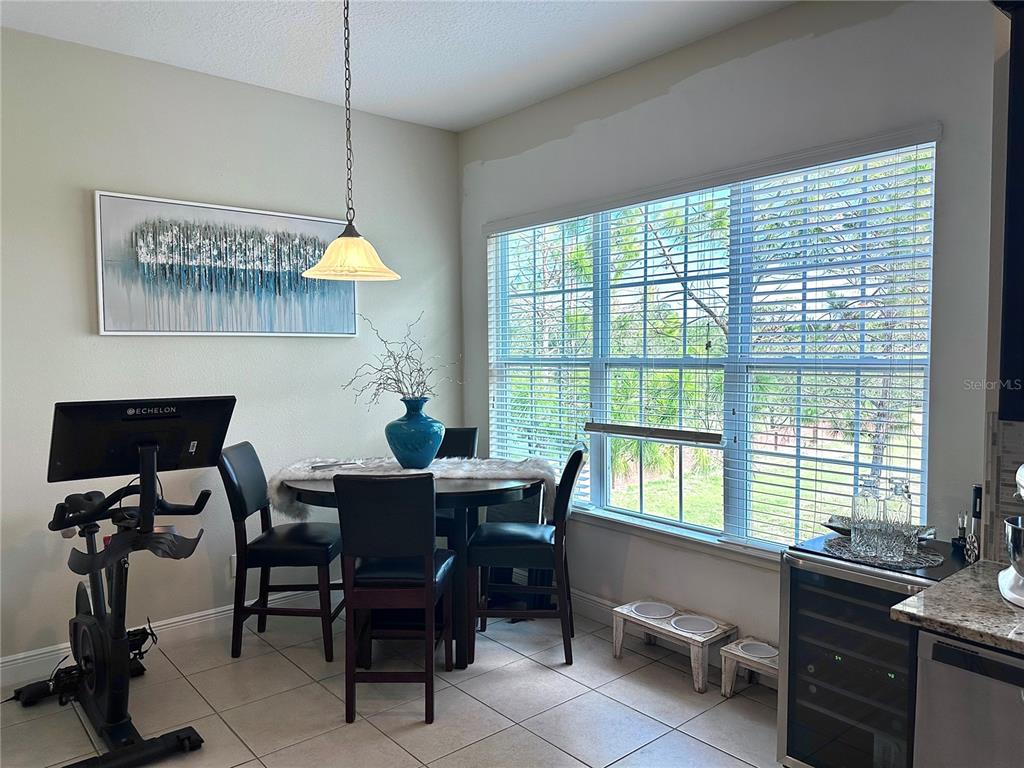 A dining area features a round table, four chairs, an exercise bike, and large windows — 1220 LOBELIA DRIVE, LAKE MARY, FL