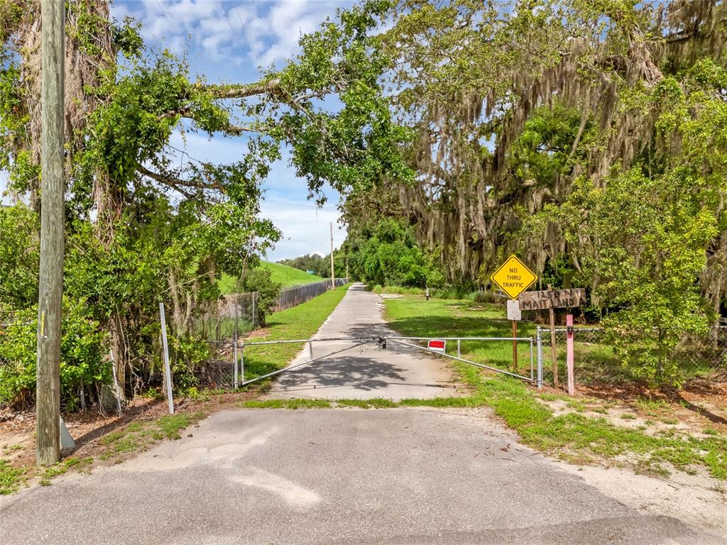 A gated paved path leads through a wooded area with a no thru traffic sign — 1250 N MAITLAND AVENUE, MAITLAND, FL
