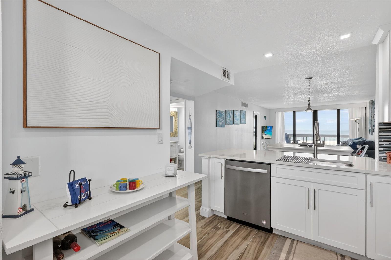 A white kitchen with stainless steel appliances and a console table in the foreground — 9940 S Ocean Drive # 202, Jensen Beach FL 34957, JENSEN BEACH, FL
