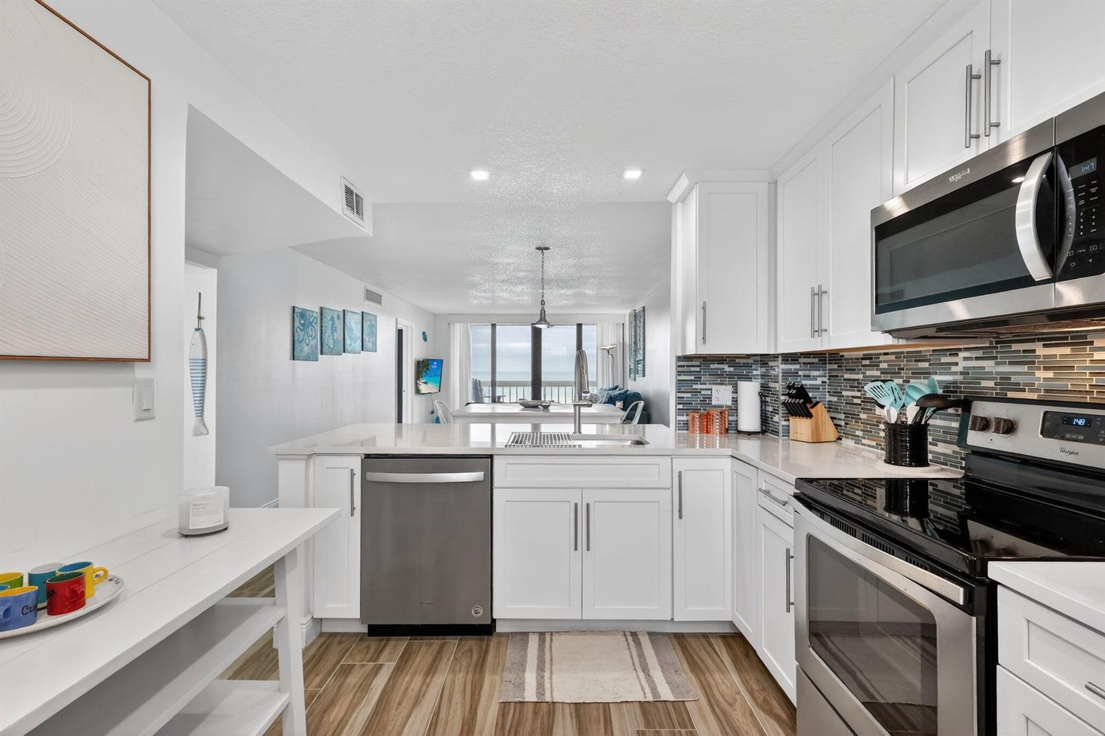A bright kitchen features white cabinets, stainless steel appliances, and a view toward the ocean — 9940 S Ocean Drive # 202, Jensen Beach FL 34957, JENSEN BEACH, FL
