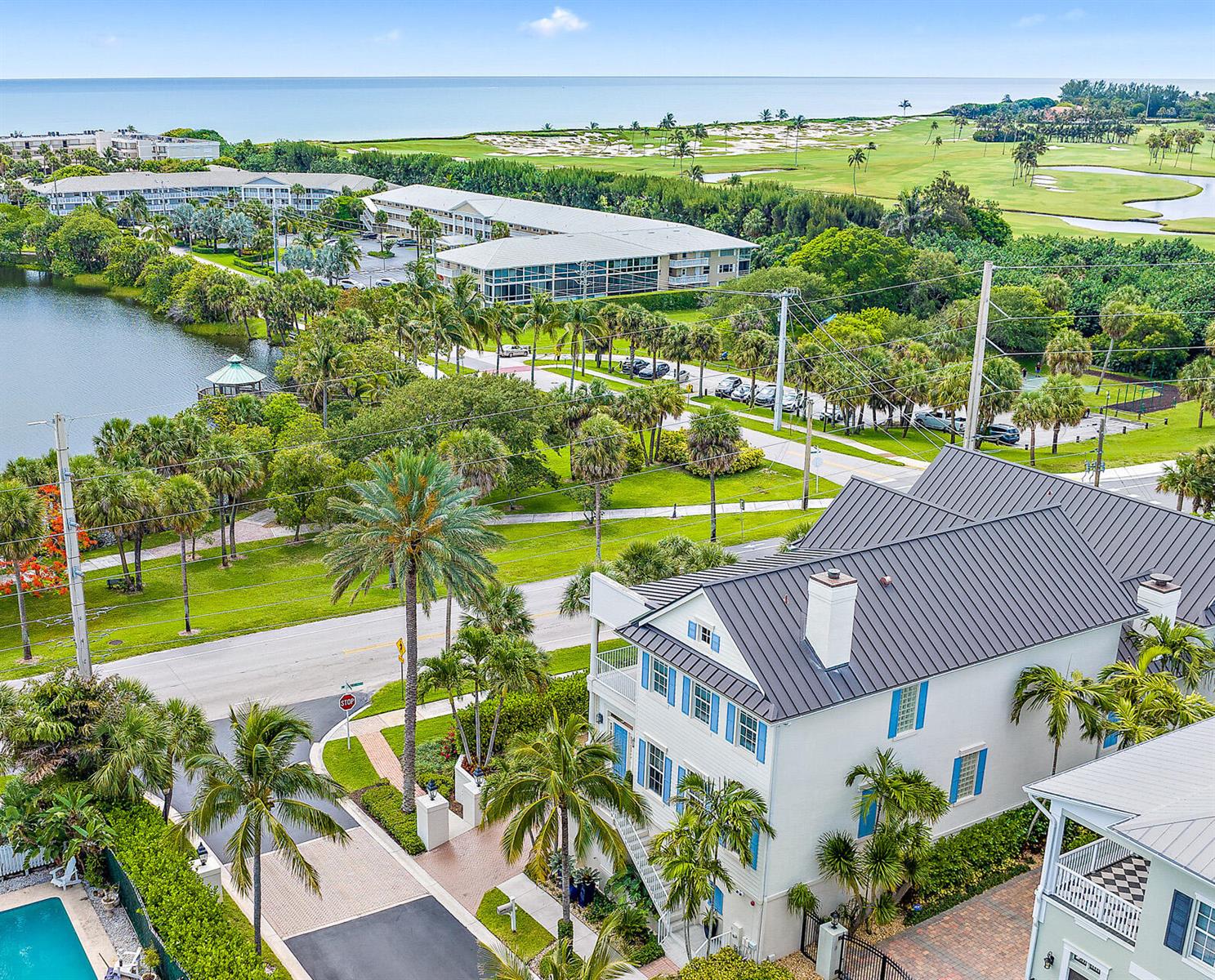 An aerial view shows a multi-story house with a metal roof near a coastal golf course — 410 Old Towne Lane, Juno Beach FL 33408, JUNO BEACH, FL