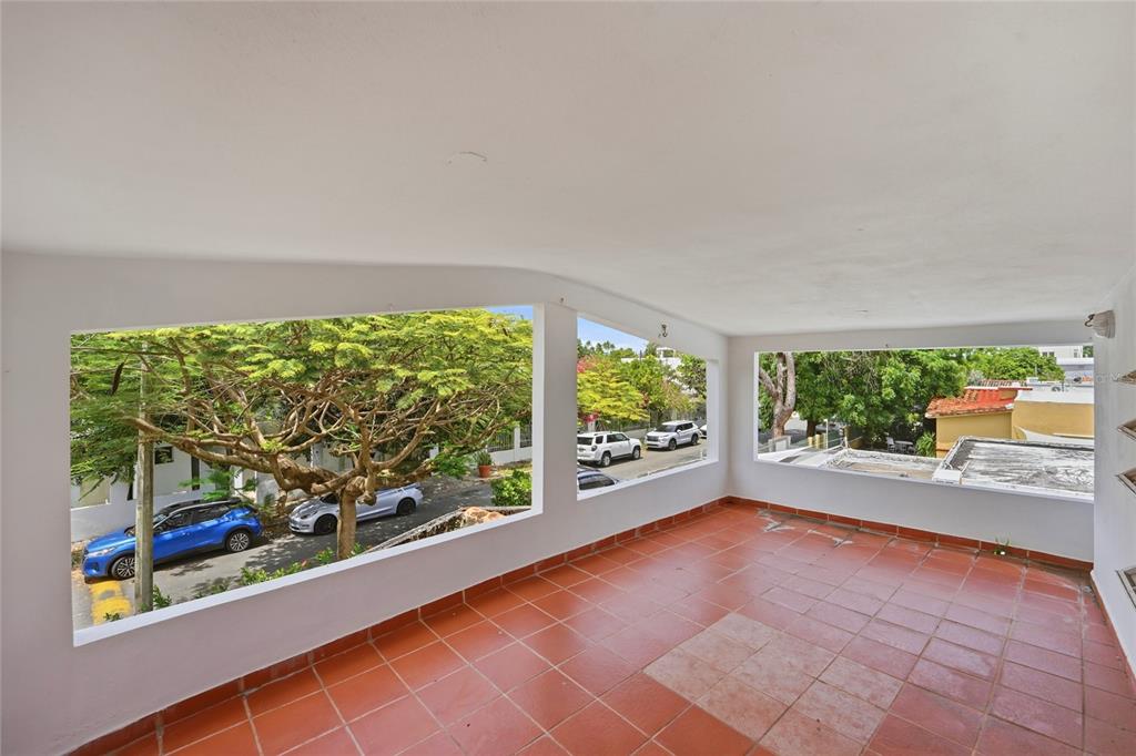 An open-air balcony with terracotta tile flooring overlooks a street with parked cars and trees — 2202 GENERAL PATTON, SAN JUAN, PR