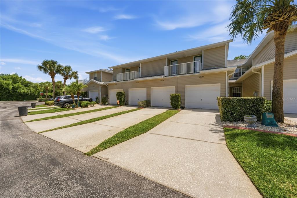 A row of two-story townhomes with attached garages and concrete driveways under a blue sky — 22128 LITTLE LAGOON COURT, LUTZ, FL