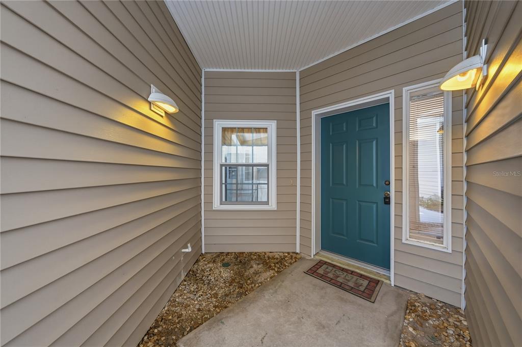 A teal front door is centered between a window and a sidelight on a porch — 22128 LITTLE LAGOON COURT, LUTZ, FL