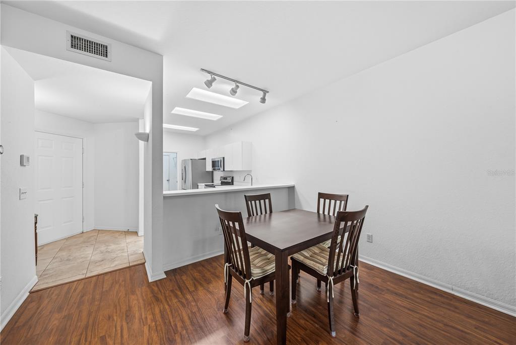 A dining area with a dark wood table and chairs sits adjacent to a kitchen — 22128 LITTLE LAGOON COURT, LUTZ, FL