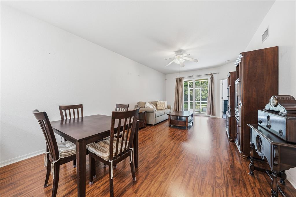 A dining area and living room with wood flooring, a ceiling fan, and sliding glass doors — 22128 LITTLE LAGOON COURT, LUTZ, FL