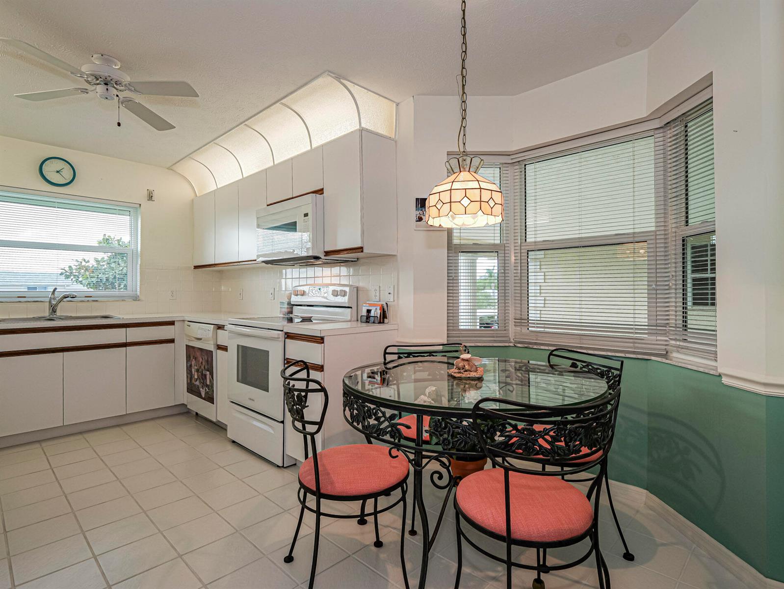 A kitchen with white cabinets, white appliances, and a glass-topped dining table in a bay — 700 Lake Orchid Circle # 209, Vero Beach FL 32962, VERO BEACH, FL