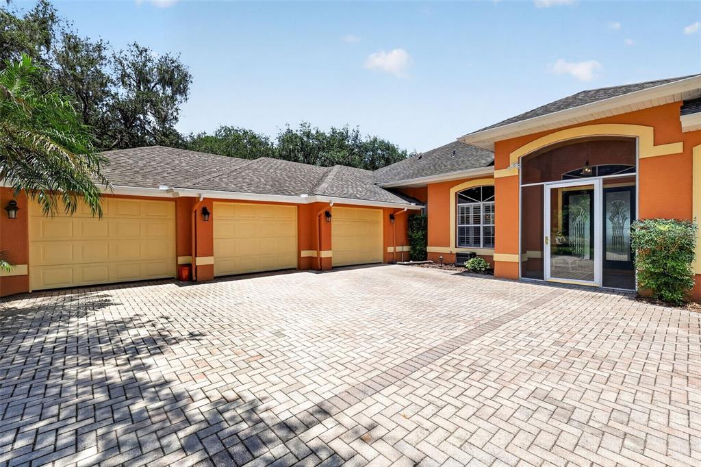 A three-car garage with light-colored doors and a paved driveway in front of a house — 29742 SQUIRREL POINT ROAD, TAVARES, FL