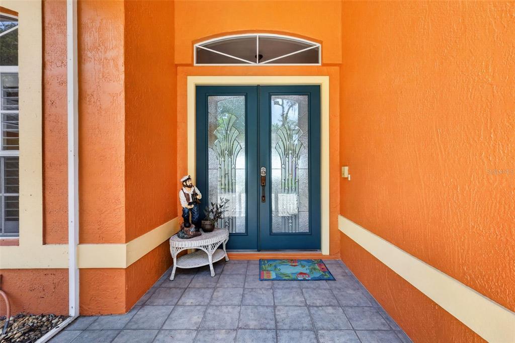 A front porch features orange stucco walls, a tiled floor, and double glass-paneled entry doors — 29742 SQUIRREL POINT ROAD, TAVARES, FL