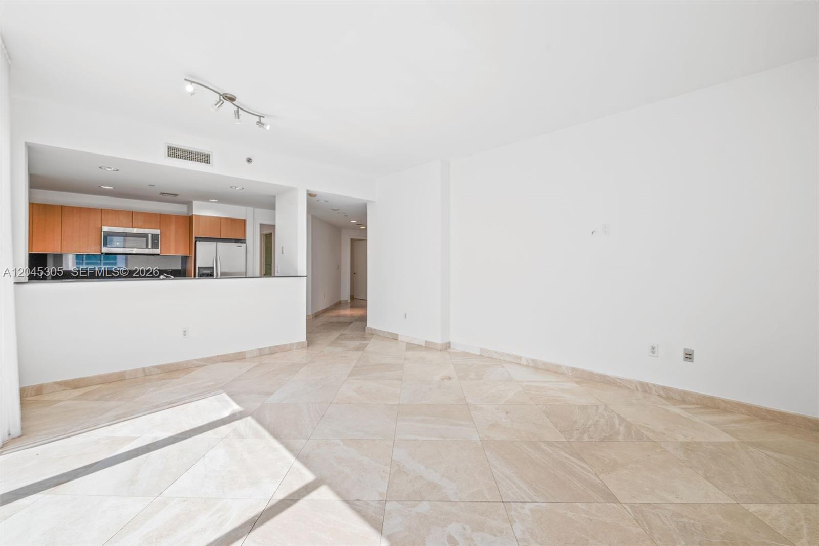 An open living area features beige tile flooring, white walls, and an adjacent kitchen — 1050 Brickell Ave # 3314, Miami FL 33131, MIAMI, FL